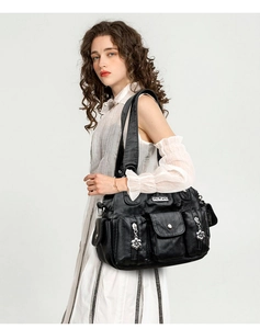 Detail view of black PU leather shoulder bag with multiple zippers and petal charms