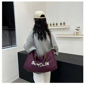 Close-up of purple travel bag with leather straps and SENGLIN logo shown on a model