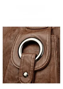 Detailed macro view of silver hardware buckle on brown lychee texture leather handbag