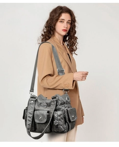Detail view of washed PU leather texture and silver hardware on a grey shoulder bag