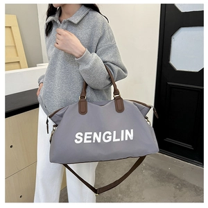 Detailed view of grey travel tote bag with leather handles and white logo on model