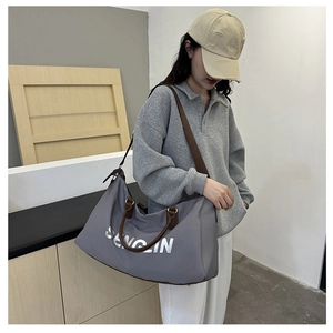 Close-up of grey large travel bag with silver SENLIN text and brown contrast straps