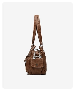 Detail view of brown faux leather bag with side pocket, silver hardware and floral charm