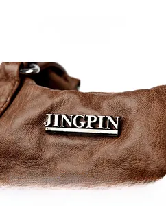 Detail of brown litchi pattern leather with polished silver metal logo plaque