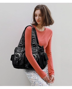 Detail of a large black washed leather shoulder bag with silver rings and multi-pocket design