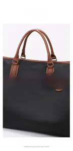 Detail of SENGLIN travel bag featuring durable black nylon and brown leather handles