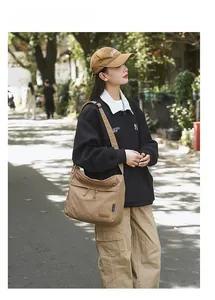 Outdoor shot of a casual khaki canvas crossbody bag with flap and zip details