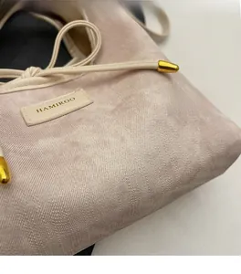 Detail of pink textured woven fabric handbag with leather brand tag and gold hardware