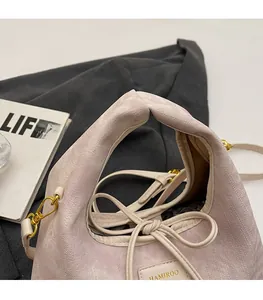 Detail of light purple fabric handbag with drawstring closure and gold buckle hardware