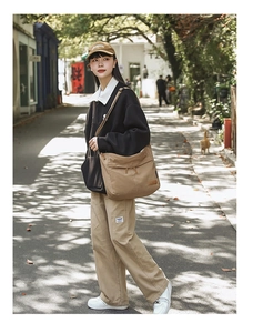 Outdoor street photo of a large khaki canvas crossbody bag in Japanese casual style