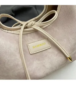Detail of pink twill fabric texture and gold brand logo plate on shoulder bag
