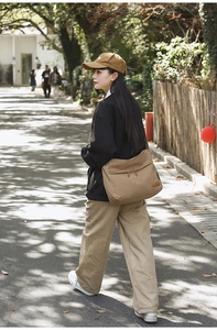Outdoor street style shot of large khaki canvas messenger bag with multiple pockets