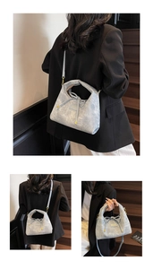 Detail of light blue textured leather crossbody bag with drawstring and gold logo