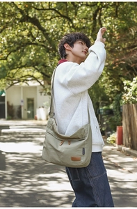 Detail of adjustable shoulder strap and leather brand tag on khaki casual messenger bag