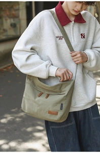 Close-up of army green messenger bag with leather straps and CHUANGMI brand tag