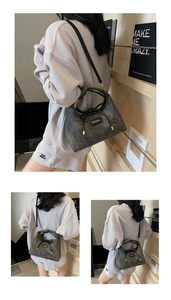 Detail of dark gray retro matte handbag with bow detail and gold metal hardware