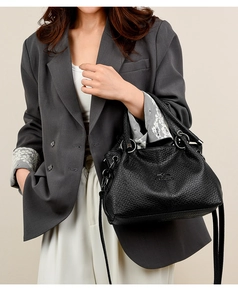 Close-up of black textured leather bag with metallic hardware and branding detail