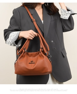 Detail of tan lychee grain leather tote bag with brand logo and adjustable strap