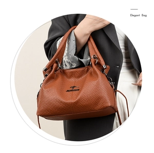 Detail of dark brown lychee leather handbag with kangaroo metal logo and ring handle