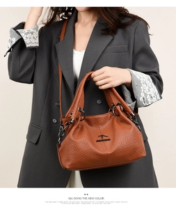 Detail of tan embossed faux leather handbag with metal logo and adjustable strap