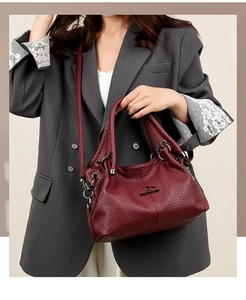Detail of dark red lychee leather texture and metallic kangaroo logo on handbag