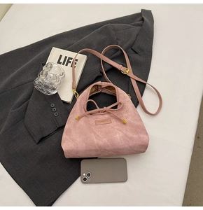Detail of pink suede handbag with bow tie and adjustable strap on office blazer