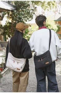 Outdoor lifestyle view of large canvas crossbody bags in beige and black colors