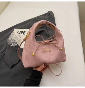 Detailed view of pink corduroy handbag with ribbon bow and gold metal logo plaque