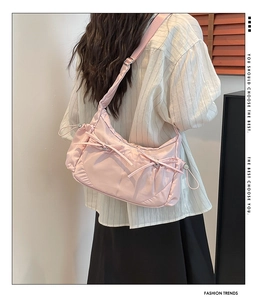 Détails d'un sac bandoulière en nylon rose avec sangle réglable et décoration nœud