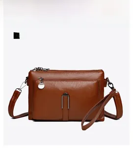 Front view of caramel brown crossbody bag showing textured leather and zipper details