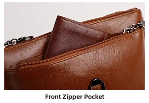 Detailed view of the front zipper pocket on a brown lychee textured leather crossbody bag