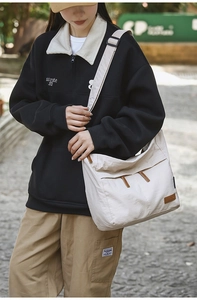 Detail of off-white multi-pocket canvas crossbody bag worn with casual streetwear outfit