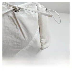 Détail d'un sac en nylon blanc montrant le tissu texturé et l'oeillet métallique