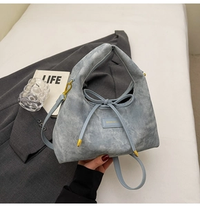 Close-up of light blue denim texture handbag with leather bow and gold metal buckle