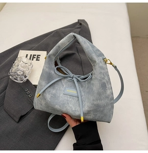 Detail of light blue crossbody bag with bow decoration and brand plaque on blazer