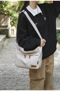 Detail view of cream canvas crossbody bag featuring functional zippers and adjustable strap