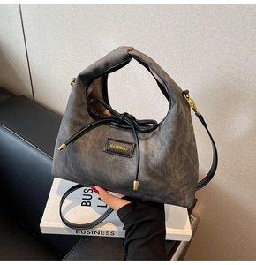 Detail of grey denim texture hobo bag with black leather bow and gold hardware