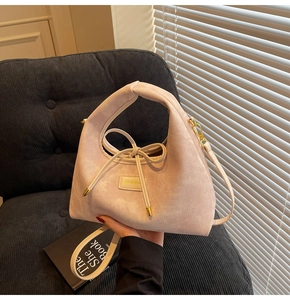 Close-up of beige handbag with drawstring bow detail and logo on corduroy background