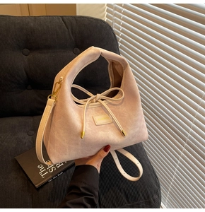 Detailed view of the light pink textured shoulder bag with a bamboo label and bow drawstring