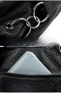 Detail of black pebbled leather handbag with silver rings and rear zipper pocket