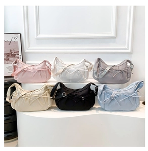 Détail de six sacs demi-lune en nylon avec nœuds et bandoulières réglables sur socle
