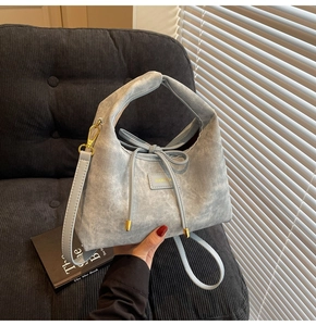 Detail view of light blue suede handbag with textured finish and golden metal buckles