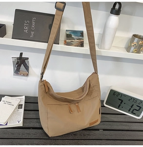 Detail view of khaki nylon crossbody bag with adjustable strap and front layered pocket