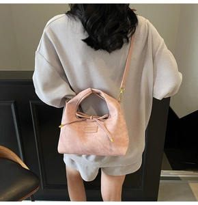 Detail of pink suede bag featuring elegant bow drawstring and gold-tone metal hardware
