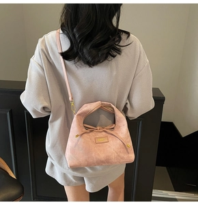 Detail view of pink suede shoulder bag featuring drawstring design and metallic accents