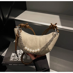 Dettaglio borsa a mezzaluna in tela con perle e manico in pelle marrone annodata
