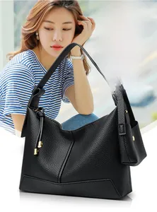 Detail of black pebbled leather tote bag with gold hardware and mini charm pouch attachment
