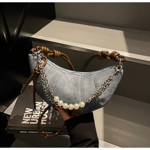 Dettaglio della borsa a mezzaluna in denim con manico in pelle e catena di perle