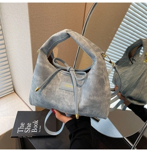 Detail showing knotted handle and bow decoration on blue fabric crossbody handbag