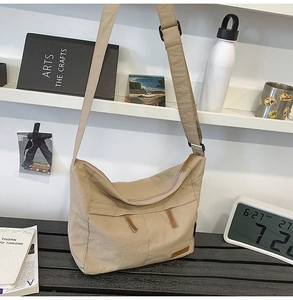 Macro shot of beige nylon crossbody bag with wide shoulder strap and metal buckles